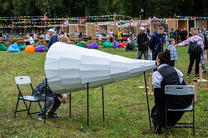 A large white cone-shaped cardboard sculpture at an outdoor Cardboardia festival