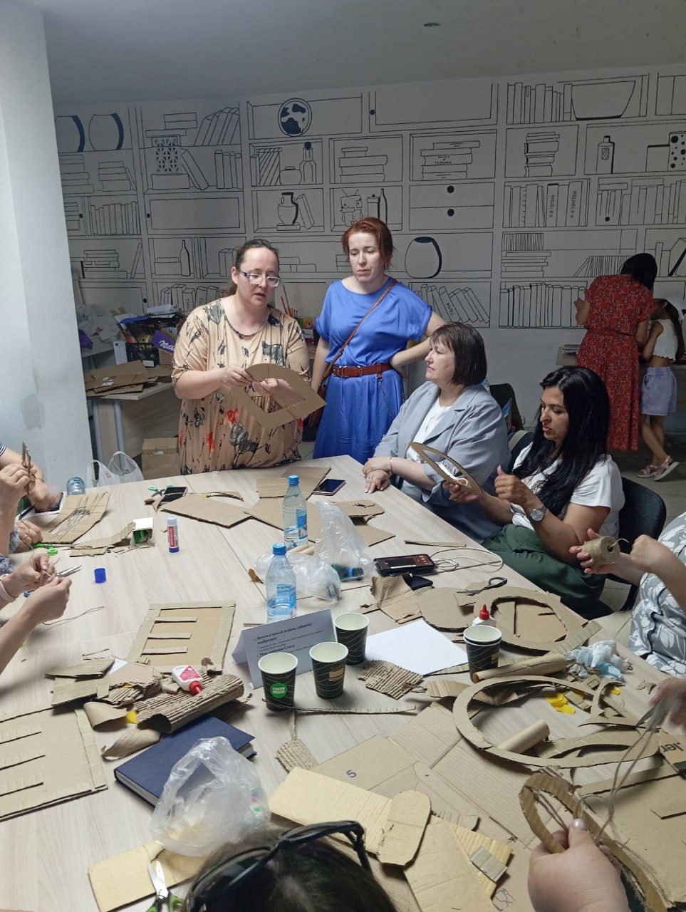 A group of adults building cardboard pieces together around a workshop table