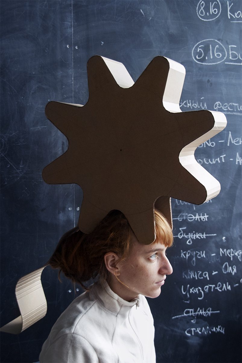 A portrait of a person wearing a giant cardboard gear as a headpiece