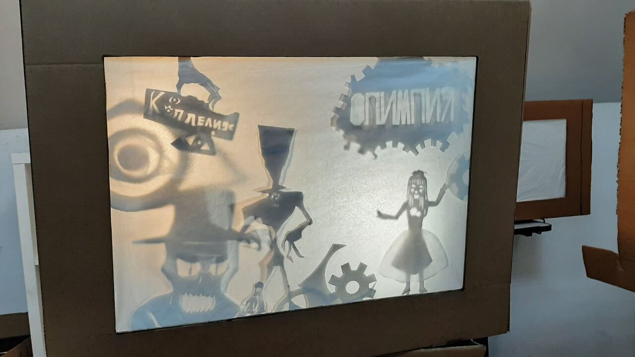 A lit cardboard shadow theater box showing silhouette figures