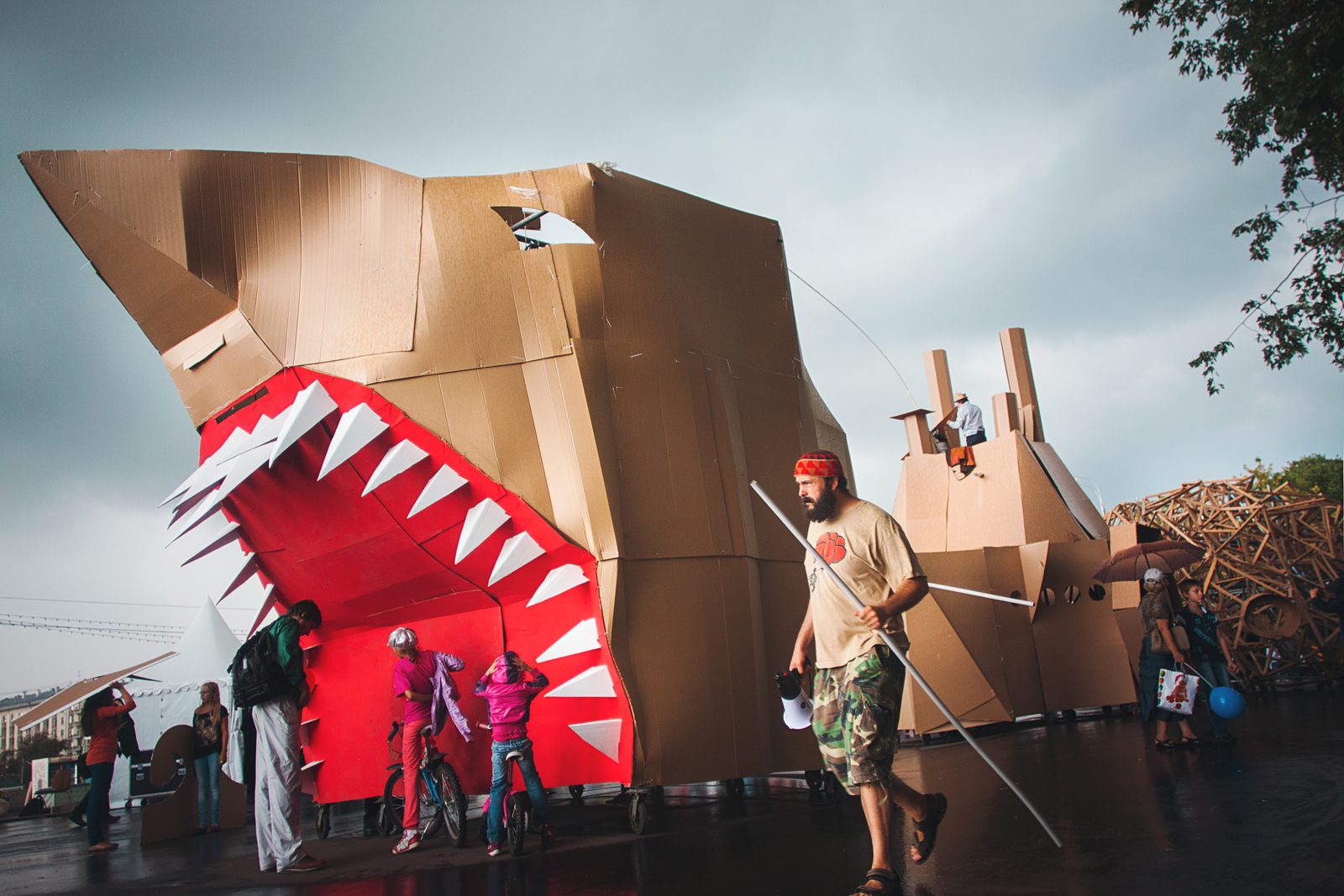 A giant cardboard shark head installation with children peeking out of its mouth